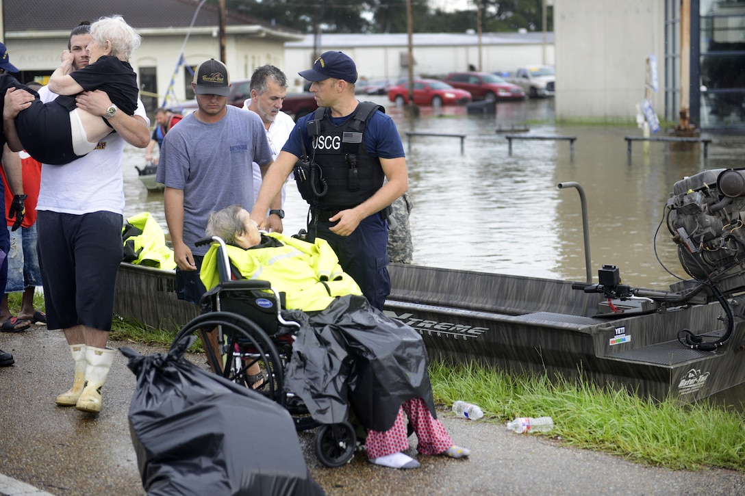 Coast Guard Chief Petty Officer Jon Tatroe, right, helps an elderly resident rescued from a seniors home during severe flooding around Baton Rouge, La., Aug. 14, 2016. Coast Guard photo by Petty Officer 3rd Class Brandon Giles