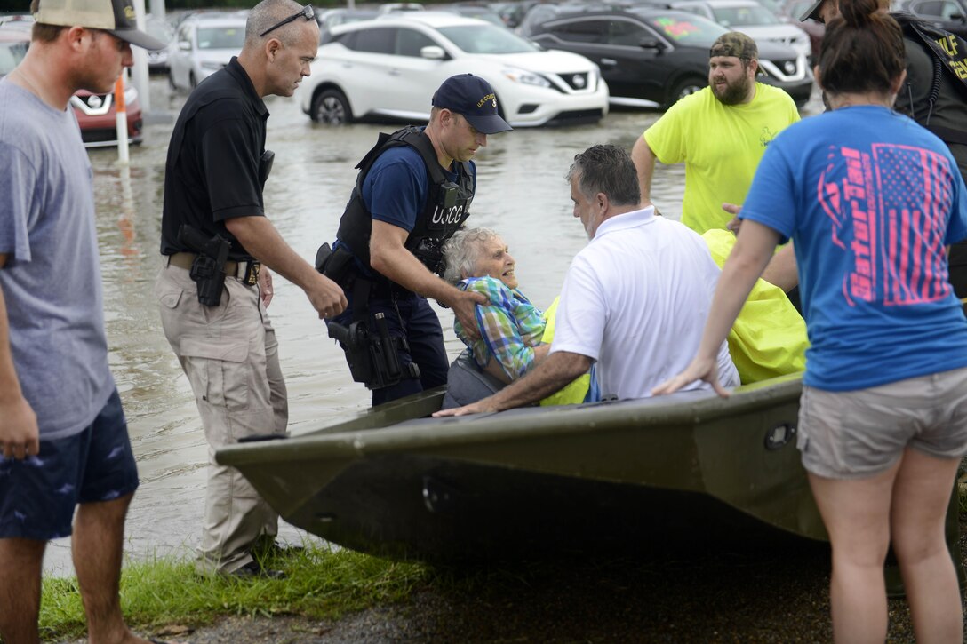 Coast Guard Chief Petty Officer Jon Tatroe, center, helps an elderly woman from a flat bottom boat after being rescued from a home for senior citizens during severe flooding around Baton Rouge, La., Aug. 14, 2016. Coast Guard photo by Petty Officer 3rd Class Brandon Giles