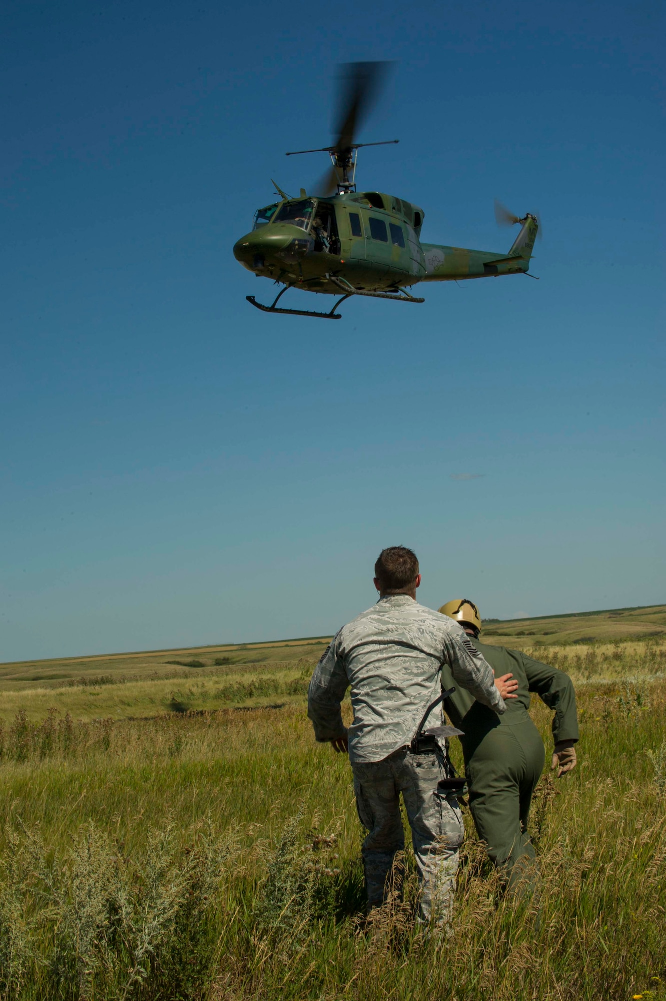 Tech. Sgt. Clifton Cleveland, 5th Operations Support Squadron survival, evasion, resistance and escape specialist, instructs an Airman to run to the helicopter during SERE training in Garrison, N.D., Aug. 11, 2016. During this portion of the training, Airmen were hoisted into the helicopter in a mock-rescue scenario. (U.S. Air Force photo/Senior Airman Apryl Hall)