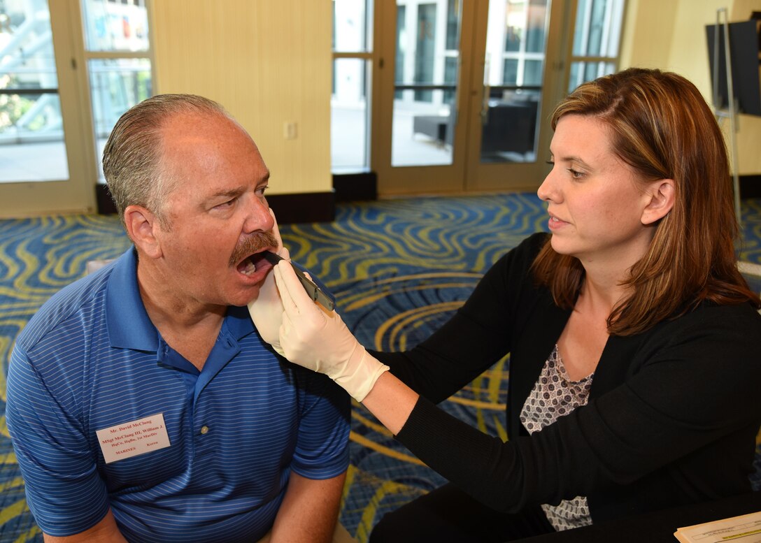 Dave McClung, nephew of Marine Master Sgt. William McClung, has his cheek swabbed for a family reference by Kerriann Meyers, Armed Forces DNA Identification Laboratory Past Accounting Section assistant technical leader, Aug. 11, 2016, at the Korean/Cold War Annual government briefings in Arlington, Virginia. McClung was one of 51 family members to give a cheek swab during the briefings.
