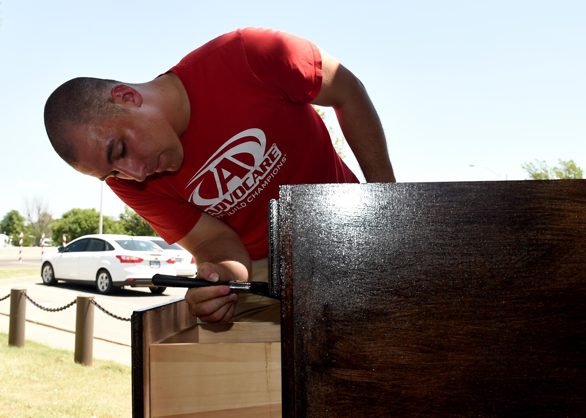 U.S. Air Force Airman 1st Class John Noble, 97th Security Forces Squadron response force member, stains a cabinet August 1, 2016, at Altus Air Force Base, Okla. 97th SFS Airmen, led by U.S. Air Force A1C Jason Martin, 97th SFS response force member, took the initiative to remodel the main gate entry facility to improve efficiency and aesthetics. (U.S. Air Force photo by Airman 1st Class Kirby Turbak/Released) 