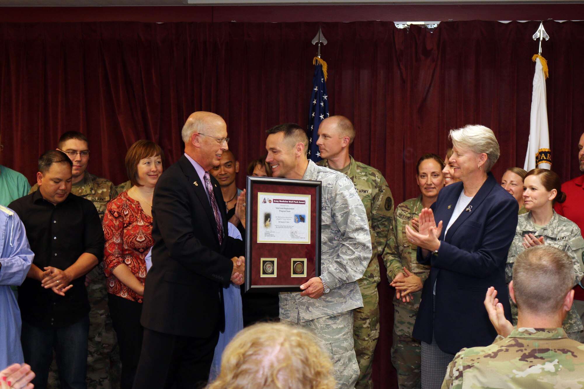Air Force Maj. William Howarth (center) accepts the U.S. Army Medicine’s 3rd Quarter Wolf Pack award from Gregg Stevens on behalf of the Total Joint Replacement Program team. (Photo by Jeff Troth)