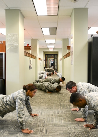 Members of the 628th Comptroller Squadron do push-ups together in their office at Joint Base Charleston – Air Base, S.C. Aug. 9, 2016. The 628th CPTS was recognized by the Health and Wellness Center (HAWC) as one of the healthiest and most fit squadrons on base. (U.S. Air Force photo by Airman 1st Class Thomas T. Charlton)