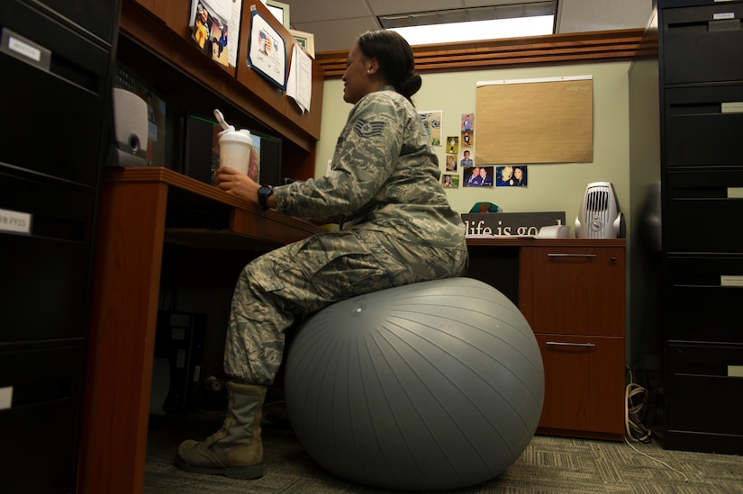 To enable fitness in her office, Staff Sgt. Tiffany Whitmore, 628th Comptroller Squadron financial analyst, sits on a medicine ball at her desk on Joint Base Charleston – Air Base, S.C., Aug. 9, 2016. Whitmore also drinks protein shakes or smoothies as a healthy alternatives to other beverages. (U.S. Air Force photo by Airman 1st Class Thomas T. Charlton)