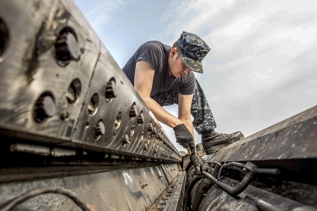 Navy Seaman Kyle Thompson secures a lube line to a catapult cylinder on the flight deck of the USS Ronald Reagan near Yokosuka, Japan, Aug. 14, 2016. The Reagan is defending maritime interests of the United States and its allies and partners in the Indo-Asia-Pacific region. Thompson is an airman. Navy photo by Petty Officer 3rd Class Nathan Burke