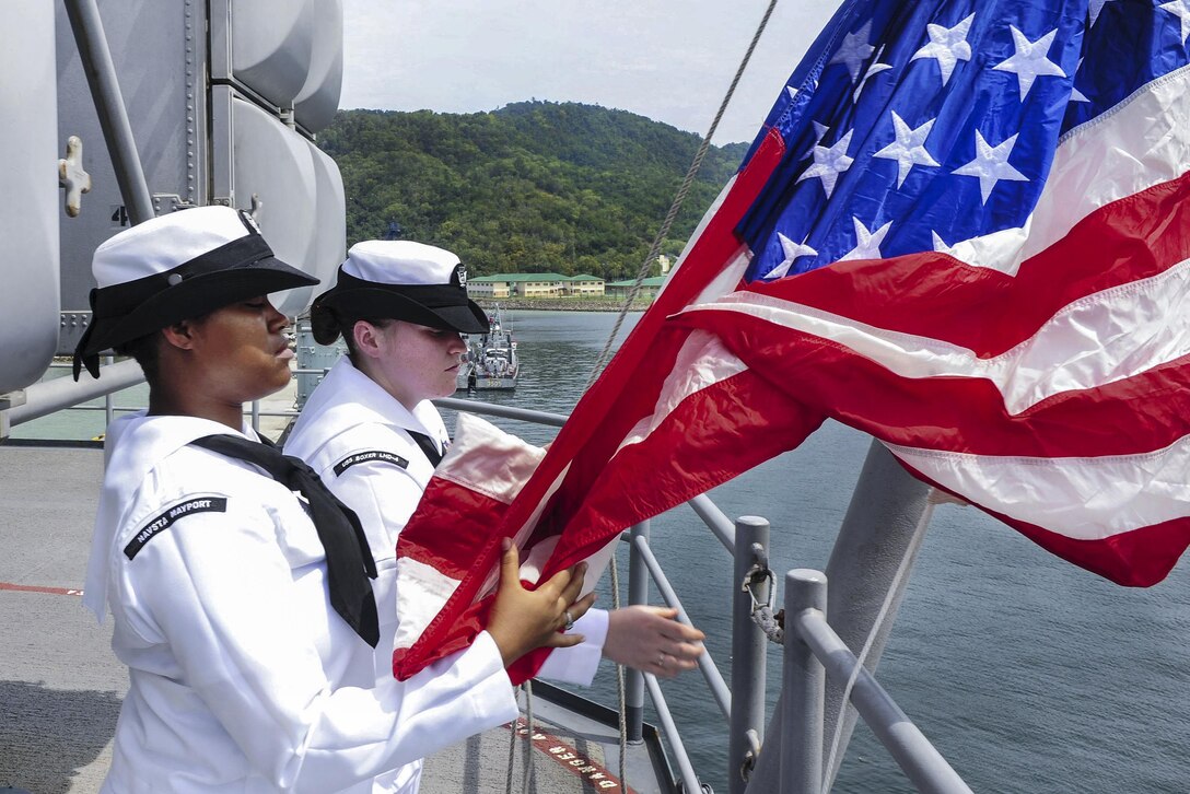 Navy Petty Officers 3rd Class Alana Marshall and Lacey Acosta hoist the national flag as the amphibious assault ship USS Boxer docks in Kota Kinabalu, Malaysia, Aug. 8, 2016. Marshall is an aviation maintenance administration specialist and Acosta is an aviation electronics technician. The Boxer is operating in the U.S. 7th Fleet area of operations to security and stability in the Indo-Asia-Pacific region. Navy photo by Seaman Eric Burgett