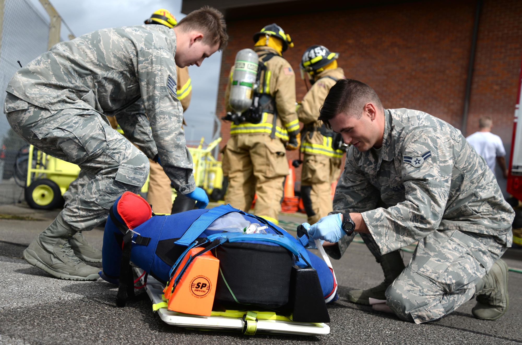 U.S. Air Force Staff Sgt. Jonathon Powell, left, and U.S. Air Force Airman 1st Class Andrew Giles, both 48th Medical Operations Squadron emergency services technicians, strap down a manikin patient in preparation for transportation Aug. 11, 2016, during an exercise on RAF Mildenhall, England. The medics simulated giving the patient supplemental oxygen and established neck and back support by using spider straps to secure the body on the board. (U.S. Air Force photo by Senior Airman Justine Rho)
