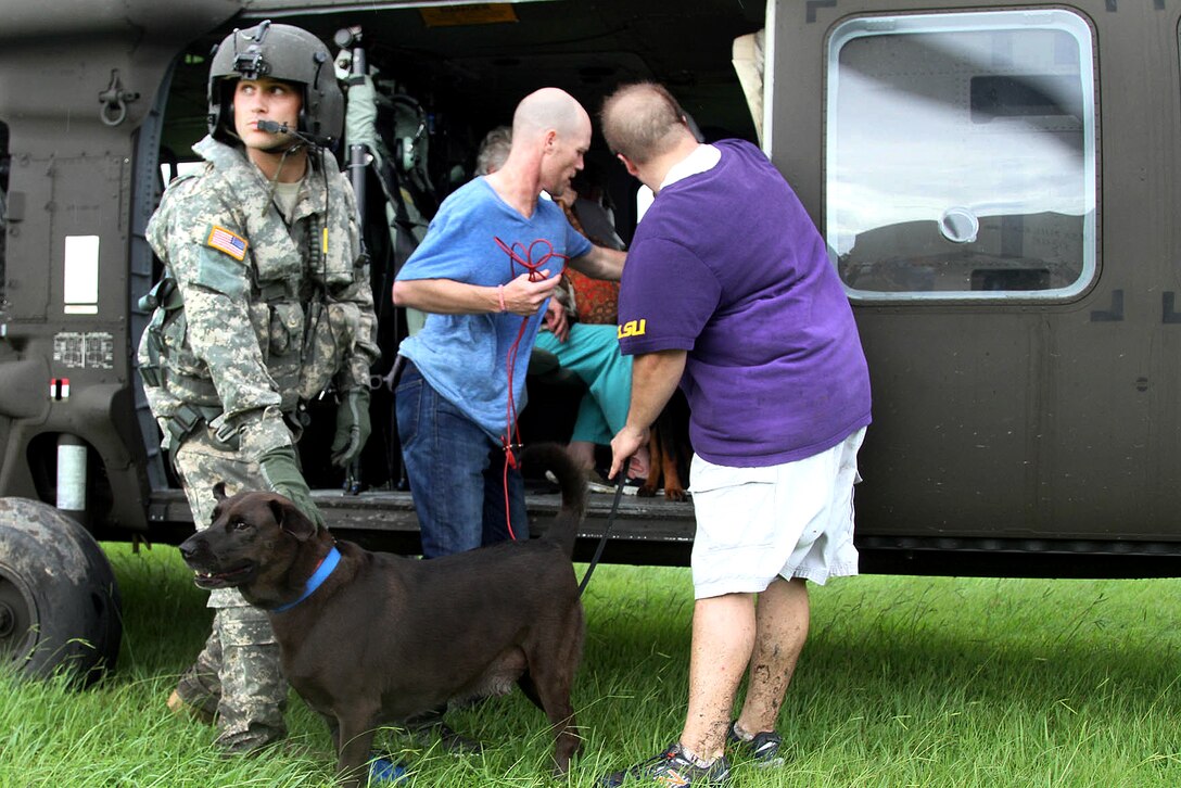A soldier helps residents and pets offload from a UH-60 Black Hawk helicopter after their rescue from floodwaters in Baton Rouge, La., Aug. 14, 2016. The soldier and helicopter crew are assigned to the Louisiana National Guard. The Louisiana National Guard has mobilized more than 1,000 personnel in response to severe flooding. Army National Guard photo by Spc. Garrett L. Dipuma