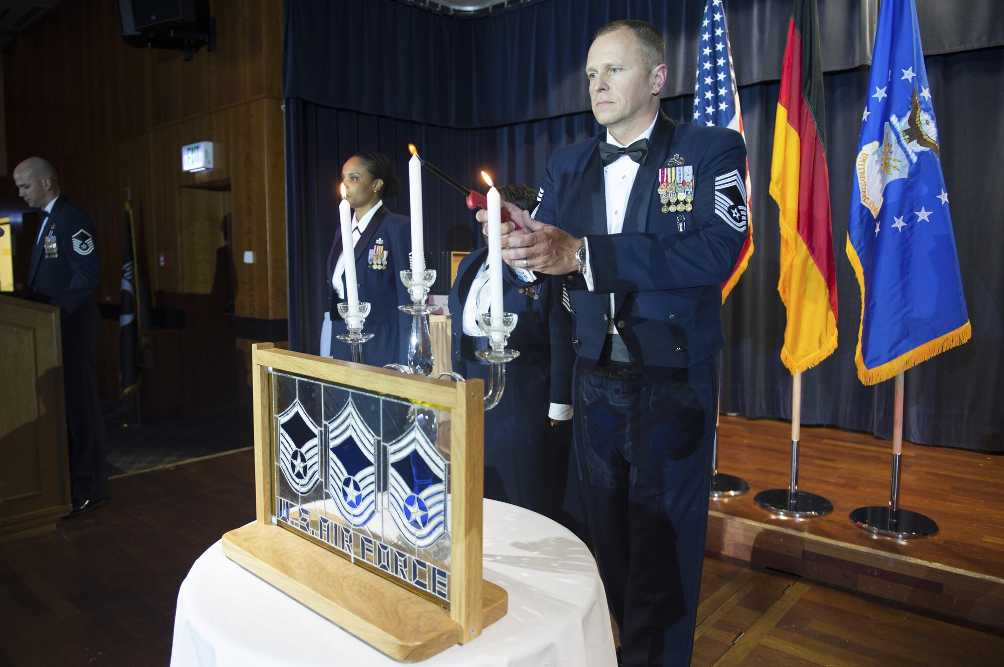 U.S. Air Force Chief Master Sgt. Scott Chord, 702nd Munitions Support Squadron chief enlisted manager, center right, lights a candle during a senior NCO induction ceremony at Club Eifel on Spangdahlem Air Base, Germany, Aug. 12, 2016. Senior NCOs lit corresponding candles symbolizing the achievement into the top tier enlisted ranks. (U.S. Air Force photo by Airman 1st Class Preston Cherry/Released)