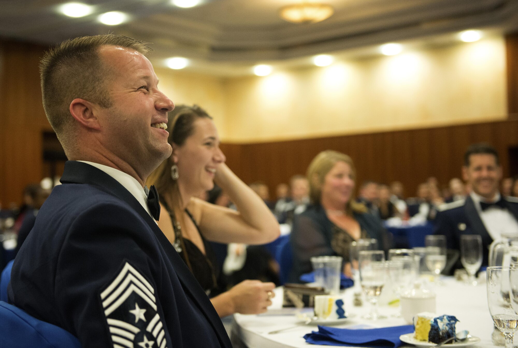 U.S. Air Force Chief Master Sgt. Edwin Ludwigsen, 52nd Fighter Wing command chief, laughs while listening to a speech during a senior NCO induction ceremony at Club Eifel on Spangdahlem Air Base, Germany, Aug. 12, 2016. More than four dozen Saber inductees walked across the stage and received recognition for their accomplishment of joining the top tier enlisted rank. (U.S. Air Force photo by Airman 1st Class Preston Cherry/Released)