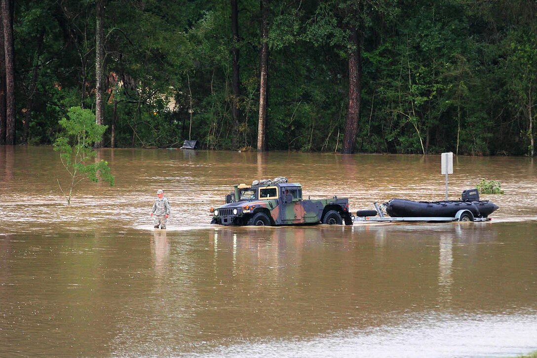 A soldier guides a Humvee towing a rescue boat through high waters during the search for flood victims in Denham Springs, Livingston Parish, La., Aug. 14, 2016. Army National Guard photo by Spc. Garrett L. Dipuma