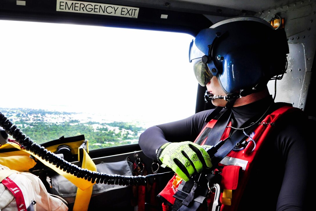 Coast Guard Petty Officer 2nd Class Stephen Nicoll scans high waters searching for stranded residents from a MH-65 Dolphin helicopter over Baton Rouge, La., Aug. 15, 2016. Nicoll is a rescue swimmer assigned to Air Station New Orleans. Coast Guard photo by Petty Officer 1st Class Melissa Leake