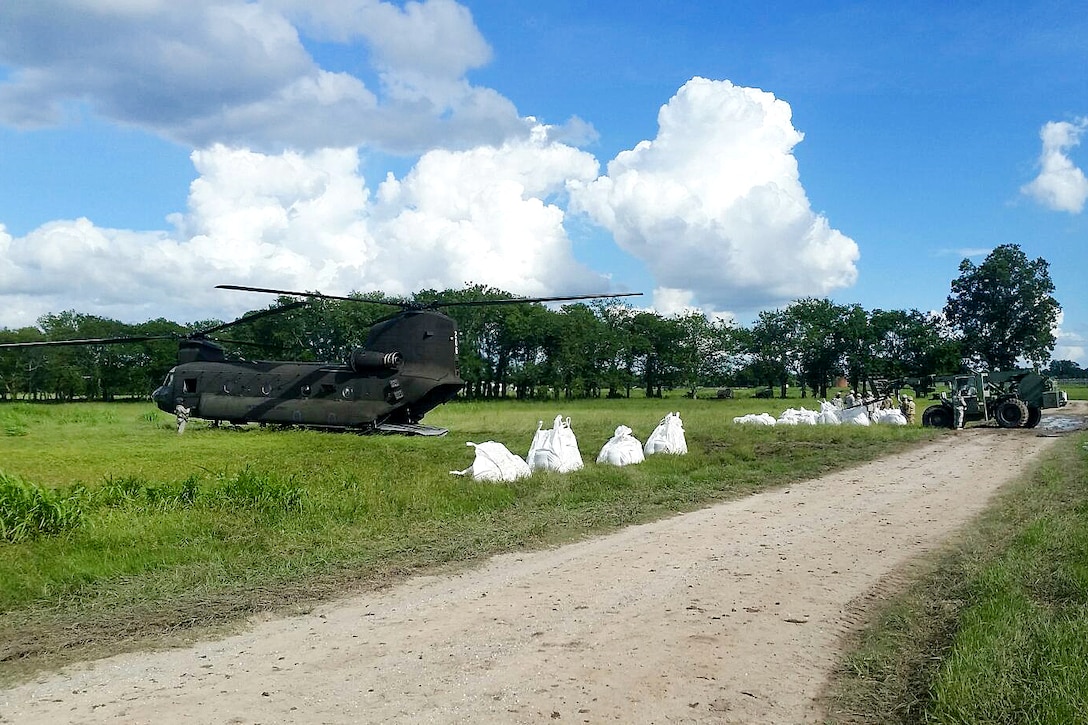 Soldiers stage large sandbags to be slingloaded by a CH-47 Chinook helicopter for flood relief operations in Baton Rouge, La., Aug. 15, 2016. The sandbags will be used to reinforce defensive barriers, reducing the chances for additional damage to roads and levees. The helicopter crew is assigned to the Mississippi National Guard. Army National Guard photo by Sgt. 1st Class Glenn Childress