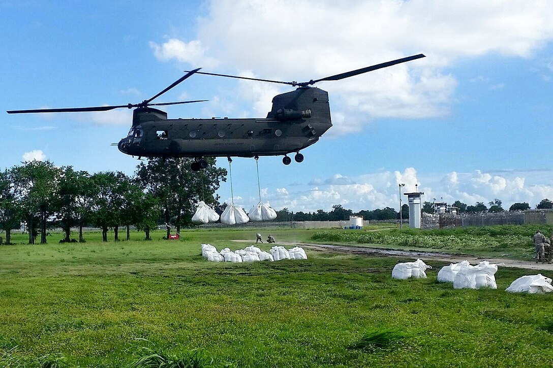 A CH-47 Chinook helicopter takes off carrying large sandbags to reinforce defensive barriers, reducing the chances of additional damage from severe flooding in Baton Rouge, La., Aug. 15, 2016. Army National Guard photo by Sgt. 1st Class Glenn Childress