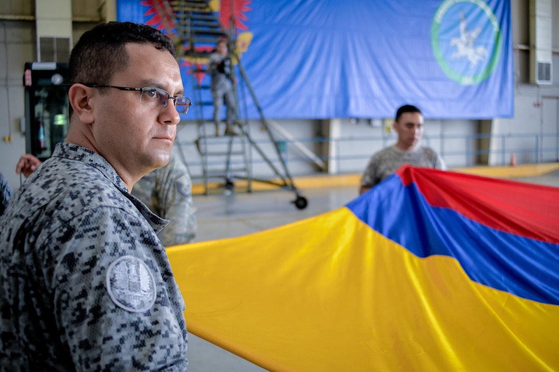 Airmen from the United States and Colombian Air Forces prepare a flag for display during Exercise Green Flag East at Barksdale Air Force Base, La., Aug. 15, 2016. Green Flag East provides pilots with simulated scenarios to train in a high-threat environment, and affords maintenance and support personnel an increased tempo in generating fully mission-capable combat aircraft. (U.S. Air Force photo/Senior Airman Mozer O. Da Cunha)