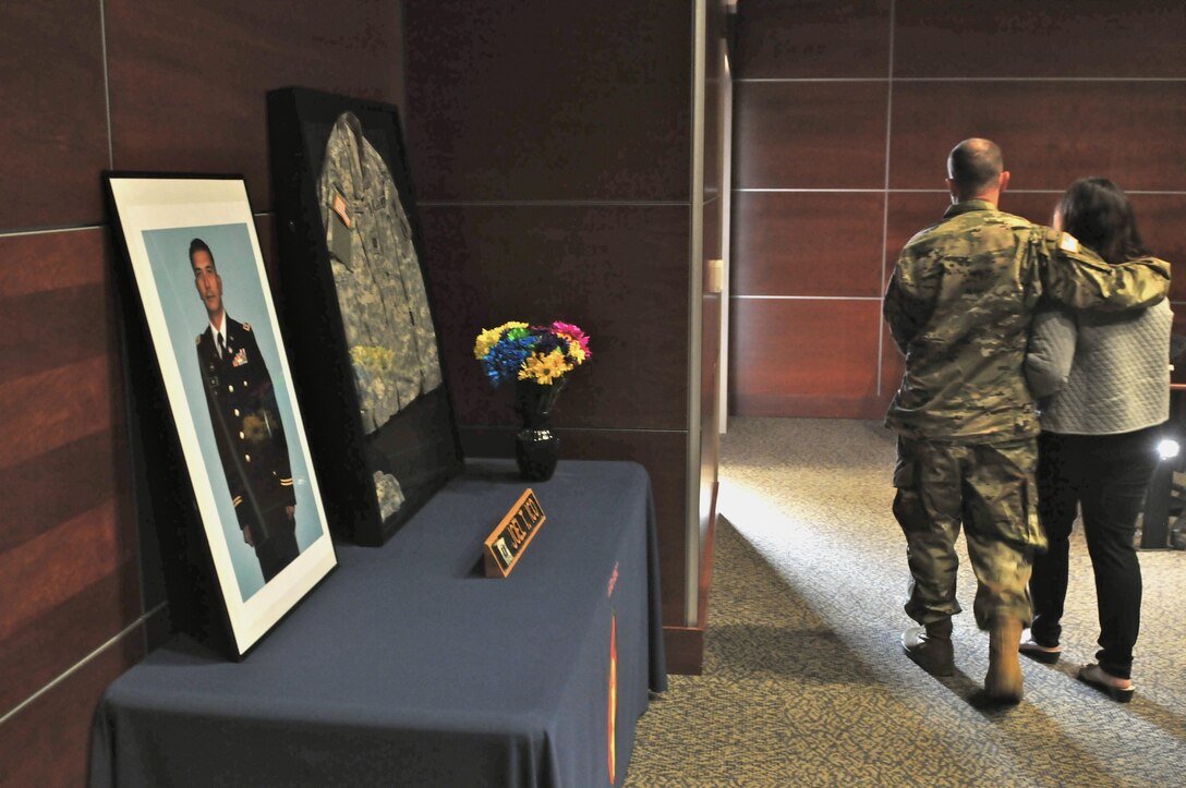 Maj. Gaetano Simeti (left), plans officer, 63rd Regional Support Command, escorts Michelle Ico (right) from the 63rd RSC auditorium, past a display of her fallen husband Capt. Joel Ico, following a memorial ceremony for Joel Ico, Aug. 14, Mountain View, Calif. Joel Ico died July 4 at the age of 41, following an accident at his residence. He is survived by his wife and 7 children. (U.S. Army Reserve photo by Capt. Alun Thomas)