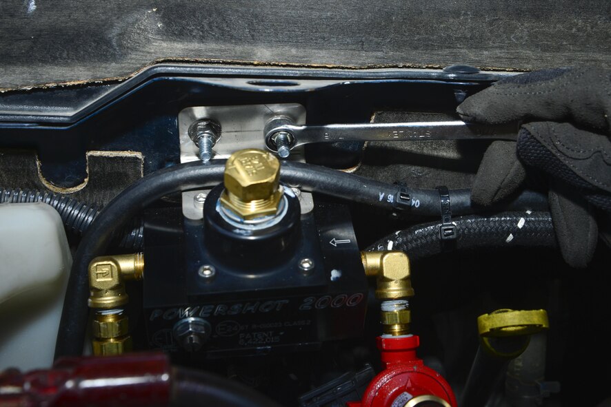 Airman 1st Class Ricardo Magana B, 436th Logistics Readiness Squadron vehicle maintenance, installs a Powershot 2,000 unit into a 436th Civil Engineer Squadron vehicle Aug. 11, 2016, at Dover Air Force Base, Del. The unit regulates the amount of propane distributed to the engine. (U.S. Air Force photo by Senior Airman William Johnson)