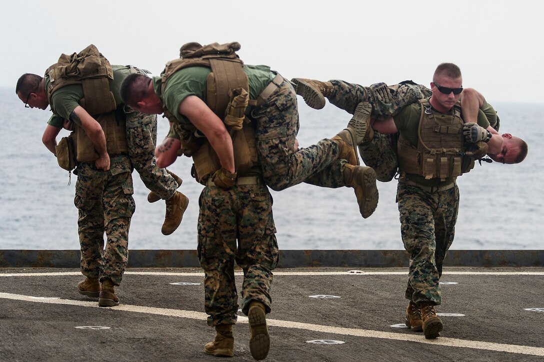 Marines practice the fireman's carry on the flight deck of the  USS Whidbey Island in the Red Sea, Aug. 10, 2016. The amphibious dock landing ship is supporting maritime security operations and theater security cooperation efforts in the U.S. 5th Fleet area of operations. Navy photo by Petty Officer 2nd Class Nathan R. McDonald