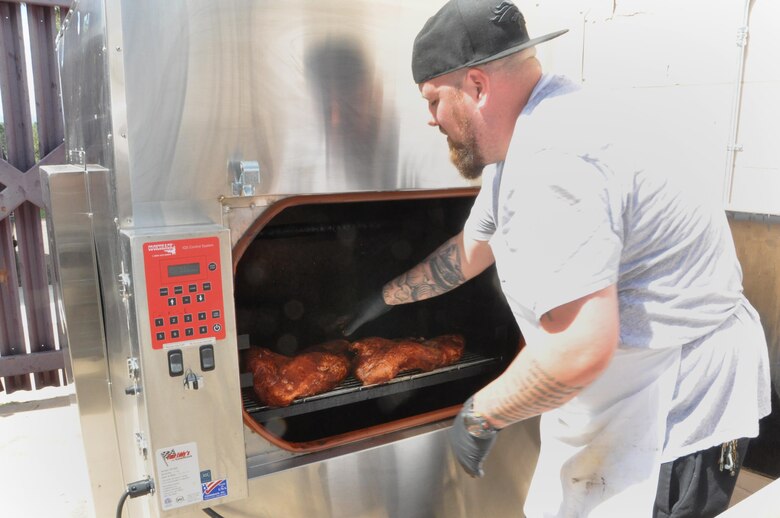Chef Kirkland Dunning puts brisket in the smoker Aug. 10, 2016, at the Greenside Grill and Smokehouse. The smoker can hold up to 300 pounds of meat, and delivers patrons a hickory-smoked lunchtime dining option. The newly remodeled restaurant re-opened in April, offering fresh, unique lunch choices with a decidedly smoky flavor. (U.S. Air Force photo by Steve Brady)