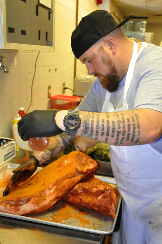 Chef Kirkland Dunning adds a spice rub to brisket before putting it in a smoker Aug. 10, 2016, at the Greenside Grill and Smokehouse. The brisket is slow-cooked for 13 hours, giving patrons a hickory-smoked lunchtime dining option. The newly remodeled restaurant re-opened in April, offering fresh, unique lunch choices with a decidedly smoky flavor. (U.S. Air Force photo by Steve Brady)