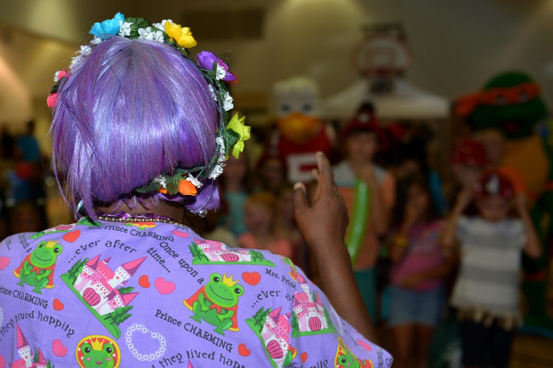 Wanda Thompson, Bubbles the clown, groups Fort Eustis community block party attendees together for a group photo at Fort Eustis, Va., Aug. 12, 2016. Bubbles hosted several games that included back-to-school prizes and raffles. (U.S. Air Force photo by Staff Sgt. Natasha Stannard)