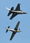 An F-16 Fighting Falcon (top) and a P-51D Mustang soar above the crowd during the Northern Neighbors Day Air Show at Minot Air Force Base, N.D., Aug. 13, 2016. The Heritage Flight showcased WWII aircraft with modern aircraft during NND. (U.S. Air Force photo/Airman 1st Class J.T. Armstrong)