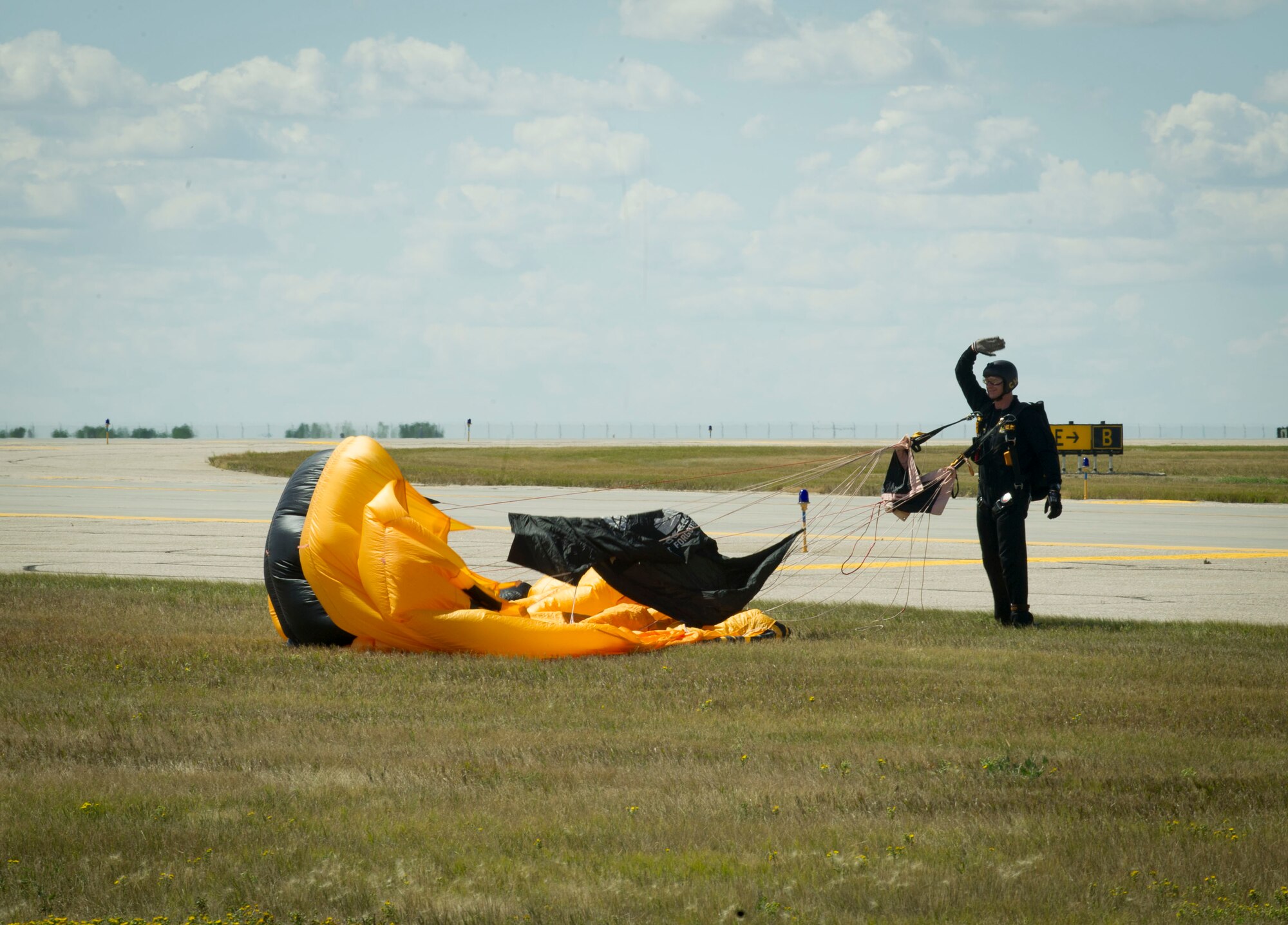 A member of the U.S. Army Golden Knights aerial demonstration team waves to the crowd after landing at Minot Air Force Base, N.D., during the Northern Neighbors Day Air Show on Aug. 13, 2016. The Golden Knights perform around the world at air shows, sports games and other performances. (U.S. Air Force photo/Senior Airman Sahara L. Fales)