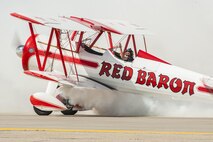 A Red Baron bi-plane pilot waves to the crowd as he finishes his act at the Northern Neighbors Day Air Show at Minot Air Force Base, N.D., Aug. 13, 2016. NND included several aerial acts including the F-16 Fighting Falcon, bi-plane crop dusters and old World War II planes. (U.S. Air Force photo/Airman 1st Class Christian Sullivan)