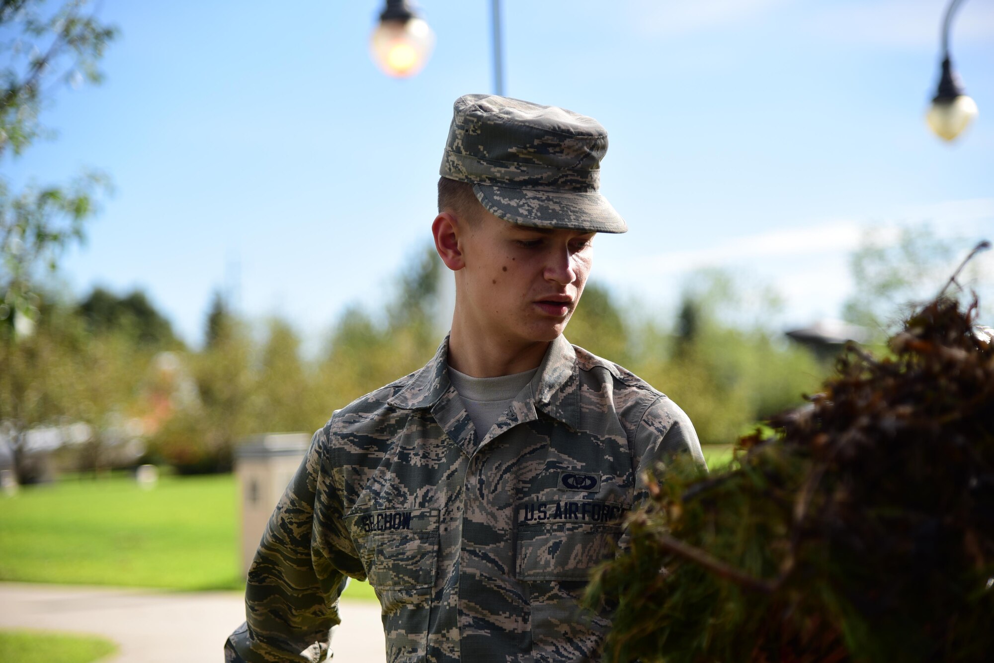 Airman 1st Class Alexander Selchow, Colorado Springs Regional Command Post, cleans up a pile of tree limbs and leaves Aug. 10, 2016 from a hail storm that struck Peterson Air Force Base, Colo. in mid-July. Airman from across the base pitched in to clean up around their work areas in the aftermath of the storm. (U.S. Air Force photo by Staff Sgt. Amber Grimm)