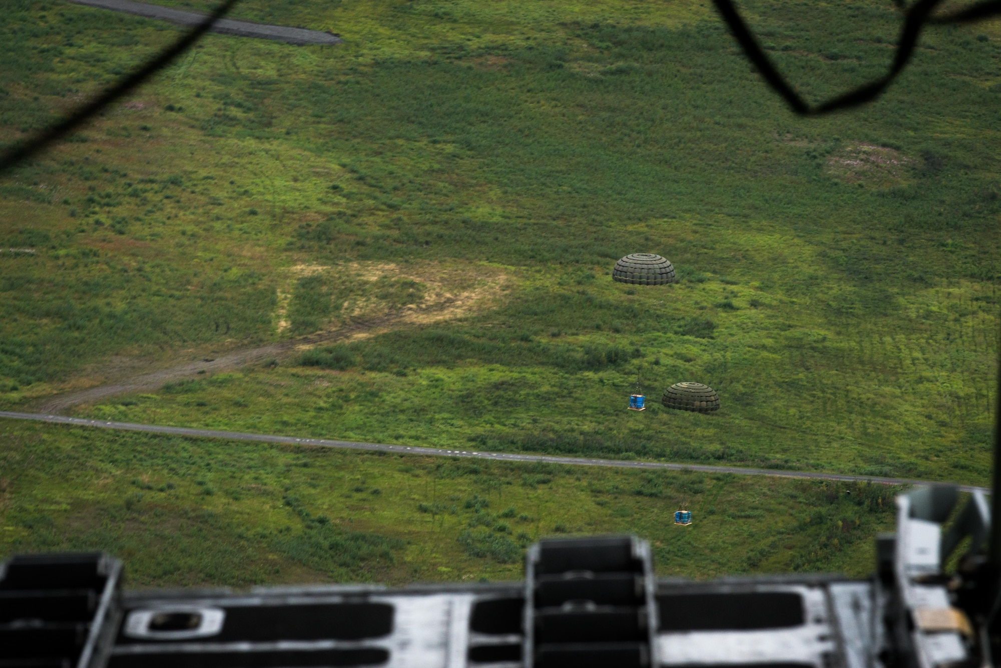 Container delivery system bundles dropped from a C-130 Hercules fall to the drop zone during Red Flag Alaska on Joint Base Elmendorf-Richardson, Alaska, Aug. 12, 2016. Bundles such as these are used to simulate airdrop procedures for supplies to ground forces. (U.S. Air Force photo by Staff Sgt. Michael Smith/Released)