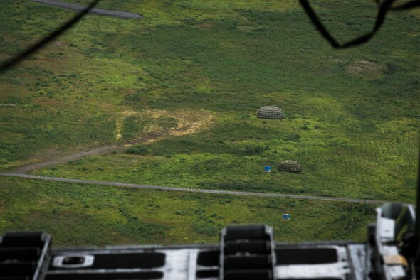 Container delivery system bundles dropped from a C-130 Hercules fall to the drop zone during Red Flag Alaska on Joint Base Elmendorf-Richardson, Alaska, Aug. 12, 2016. Bundles such as these are used to simulate airdrop procedures for supplies to ground forces. (U.S. Air Force photo by Staff Sgt. Michael Smith/Released)