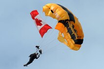 A member of the U.S. Army Golden Knights parachutes down with the Canadian flag during the Canadian national anthem at Northern Neighbors Day Air Show at Minot Air Force Base, N.D., Aug. 13, 2016. The team performs parachute demonstrations at air shows, major league football and baseball games, and other special events, connecting the Army with the American people. (U.S. Air Force photo/Senior Airman Kristoffer Kaubisch)