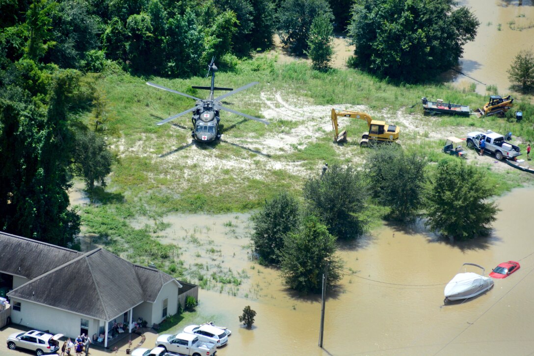 A UH-60 Black Hawk medevac helicopter crew, lower left, provides medical aid after responding to a call for assistance near Denham Springs, La., Aug. 15, 2016, following more than 30 inches of rainfall since Aug. 12. Army National Guard photo by 1st Sgt. Paul Meeker