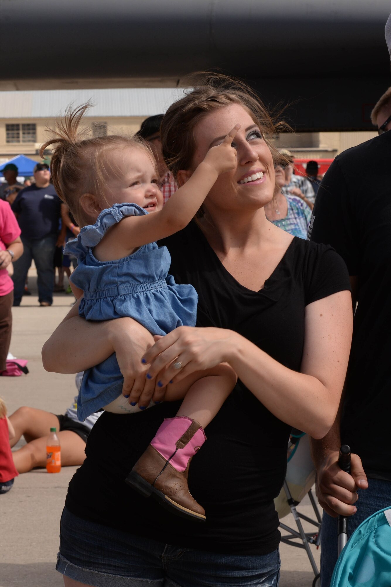 A young girl points to the sky during the Northern Neighbors Day Air Show at Minot Air Force Base, N.D., Aug. 13, 2016. Patrons were able to enjoy aerobatic stunts performed by Kent Pietsch in the Jelly Belly aircraft. (U.S. Air Force photo/Airman 1st Class Jessica Weissman)