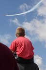 A child sits on the shoulders of his father during the Northern Neighbors Day Air Show at Minot Air Force Base, N.D., Aug. 13, 2016. The Red Baron is a historic replica aircraft from World War II. (U.S. Air Force photo/Airman 1st Class Jessica Weissman)