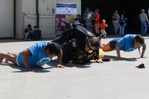 U.S. Army Staff Sgt. Trey Martin, a tandem free fall videographer for the U.S. Army Golden Knights black demonstration team, does pushups with children at the Northern Neighbors Day Air Show at Minot Air Force Base, N.D., Aug. 13, 2016. Martin has logged more than 2,950 freefall parachute jumps and 15 military static line jumps. (U.S. Air Force photo/Airman 1st Class Jessica Weissman)