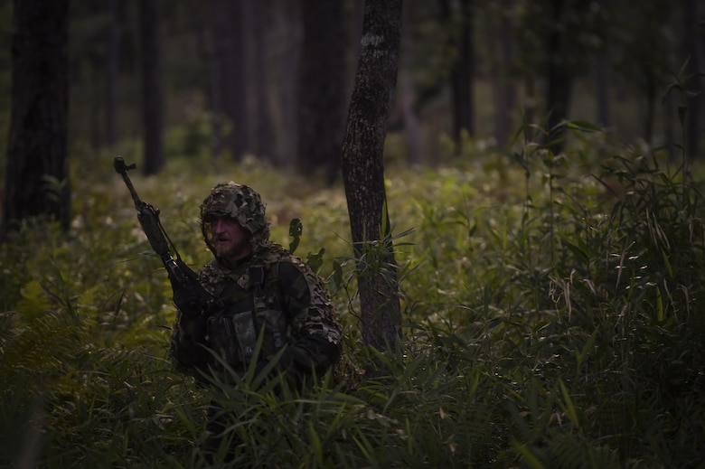 A 352nd Battlefield Airman Training Squadron Combat Control School instructor stalks CCT students as an opposing force during a tactics field training exercise at Camp Mackall, N.C., Aug. 3, 2016. The FTX is a culmination of tactics learned in the first year of the CCT pipeline; which entails weapons handling, team leader procedures, patrol base operations, troop leading and small unit tactics under fire in one mission. (U.S. Air Force photo by Senior Airman Ryan Conroy)
