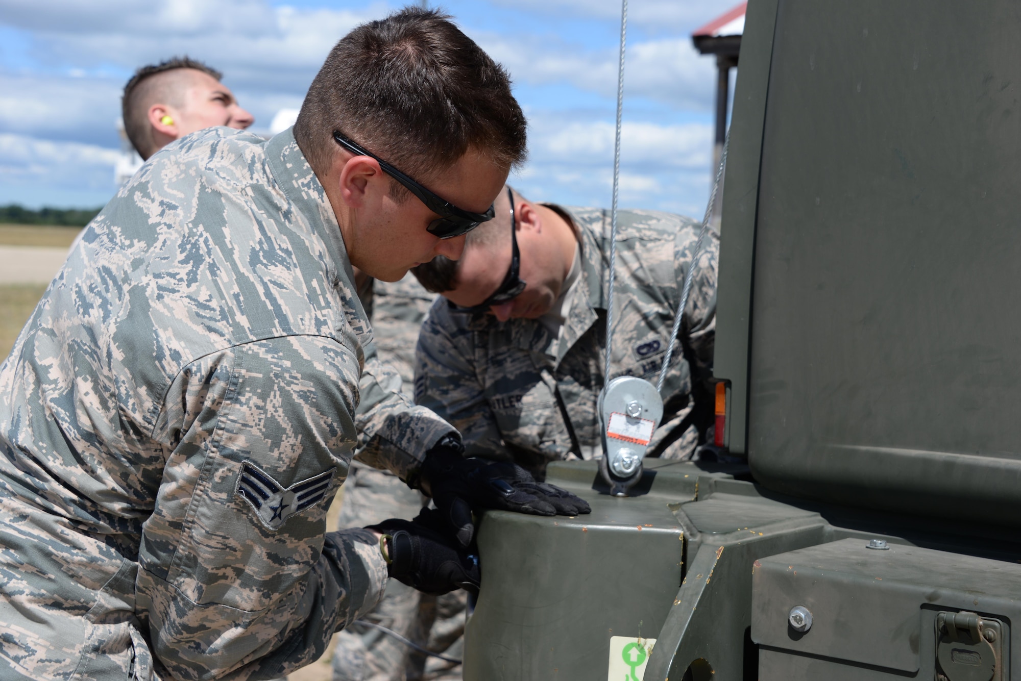 Senior Airman Ryan Fennessey, left, and Senior Airman Michael Butler, right, 821st Contingency Response Support Squadron air transportation journeymen, install a bumper on a 10k all-terrain forklift at Grayling Army Airfield, Michigan, during Exercise Northern Strike, Aug. 7, 2016.. Air transportation Airmen received on-the-job training in order to learn vehicle maintenance on the all-terrain forklift. (U.S. Air Force photo by Senior Airman Amber Carter)