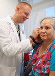 Maj. (Dr.) R. Anderson (left), internal medicine physician, inserts acupuncture needles in Nelda Rodriguez’s ears to relieve pain from her neck at Brooke Army Medical Center recently.