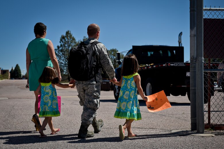 A reunited family walks hand-in-hand to their vehicle after departing the flightline at Peterson Air Force Base, Colo., Aug. 13, 2016. Airmen from the 4th Space Control Squadron just returned from deployment and rushed to meet their waiting families. (U.S. Air Force photo by Senior Airmen Rose Gudex)