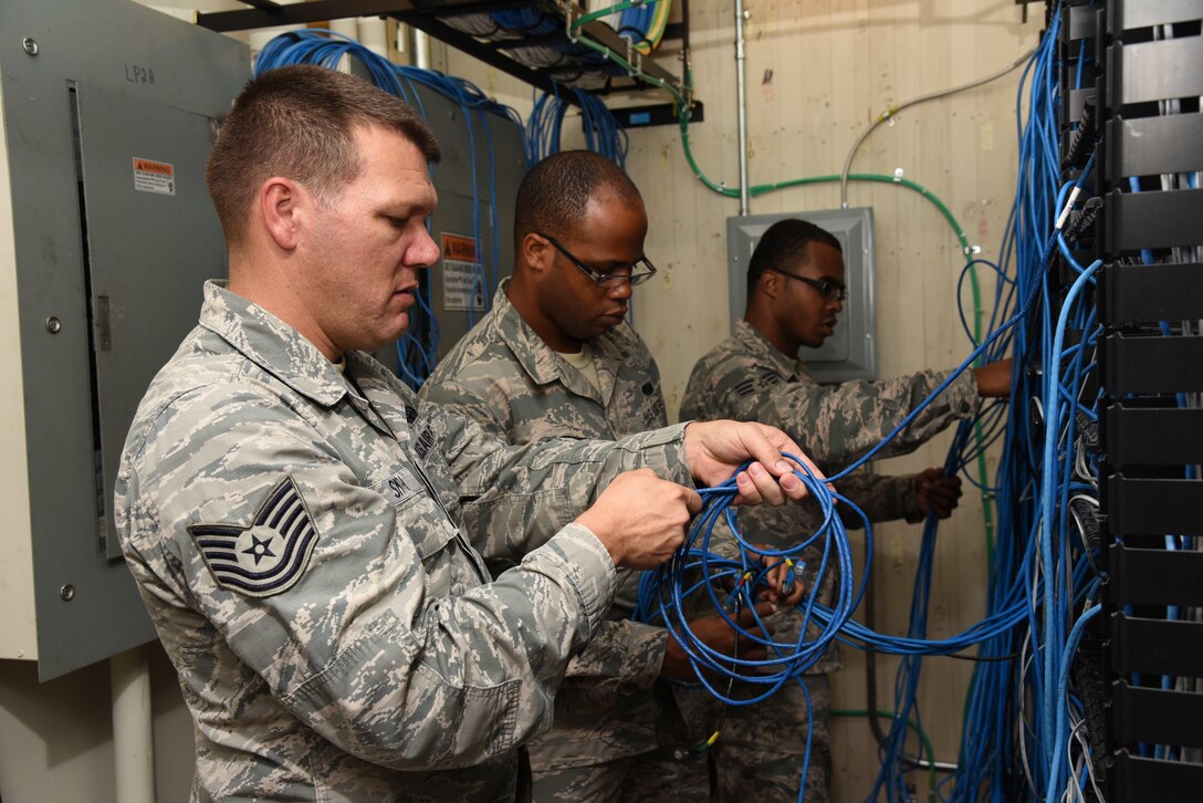 Tech. Sgt. Joshua Smith and Senior Airmen Jacob Tatum and Dontavius Morrissette (left to right), 403rd Communications Flight cybertransport technicians, hook up cables to panels that connect 403rd Wing computers to the Air Force network August 7, 2016, at Keesler Air Force Base, Mississippi. The flight’s citizen Airmen are tasked with repairing, maintaining and updating the 403rd Wing’s computer equipment and providing network connectivity. (U.S. Air Force photo/Tech. Sgt. Ryan Labadens)