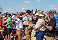 Spectators applaud the performance of one of the aerial demos during the Northern Neighbors Day Air Show at Minot Air Force Base, N.D., Aug. 13, 2016. The performance of the P-51 D Mustang was able to get several people out of their seats as they witnessed the fighter jet soar through the sky. (U.S. Air Force photo/Airman 1st Class Jonathan McElderry)