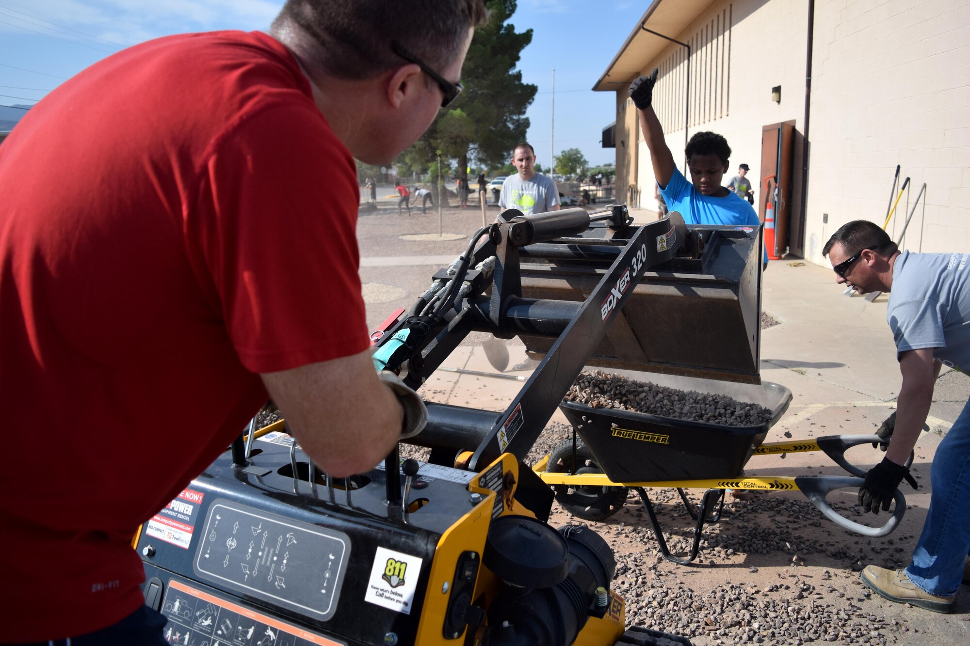 Volunteers use equipment to dump loads of rock into a wheel barrow during a beautification project at Sierra Elementary School in Alamogordo, N.M., on July 30, 2016. The team spent a total of 234 man hours during six separate days finishing the task. (U.S. Air Force photo by Staff Sgt. Eboni Prince)