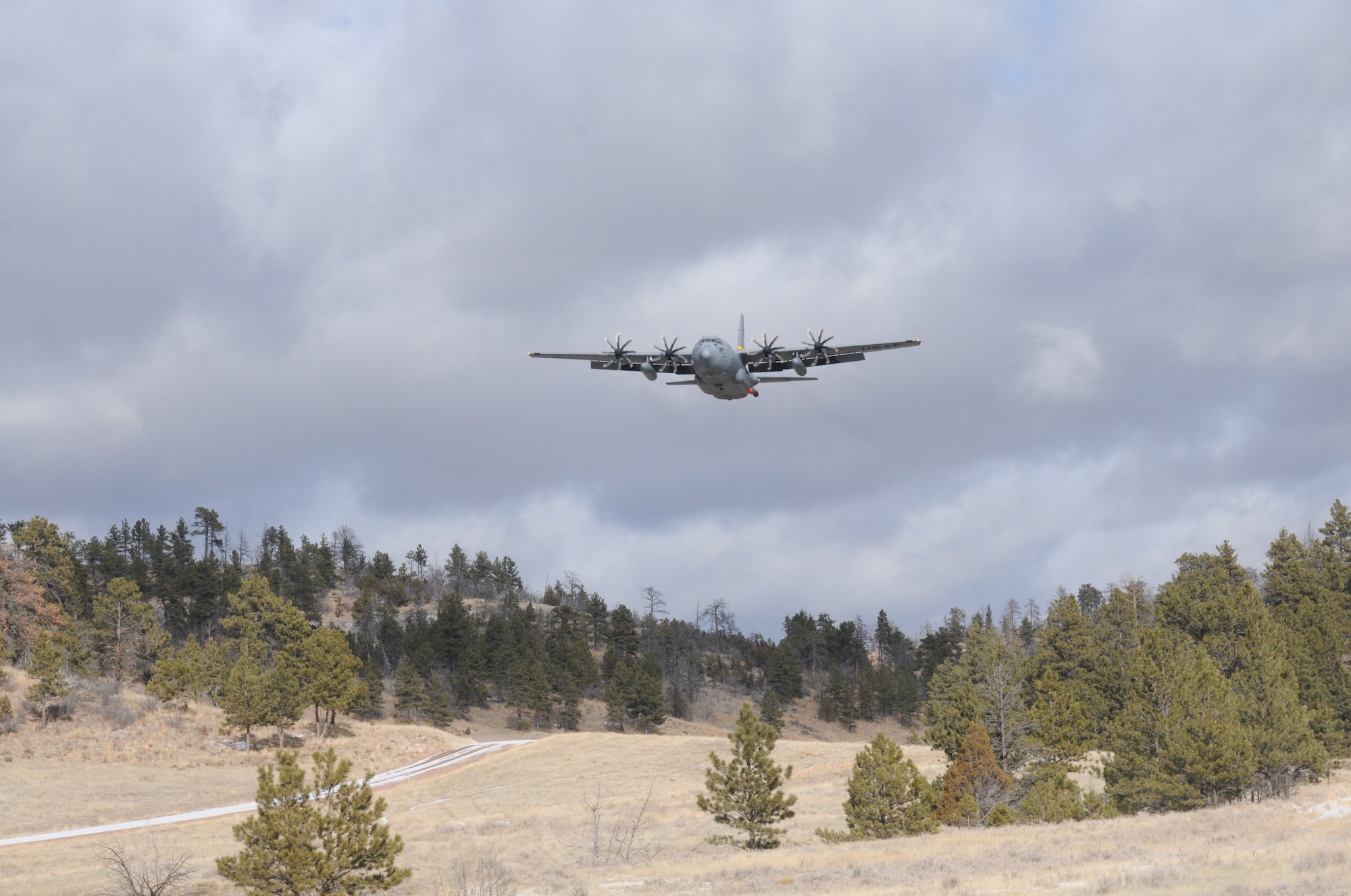 A C-130H Hercules aircraft assigned to the 153rd Airlift Wing, Wyoming Air National Guard flies over Camp Guernsey, Wyoming during Modular Airborne Fire Fighting System training. The training is being performed using a C-130 modified with an Electronic Propeller Control System and eight-bladed propeller system. (Courtesy photo)