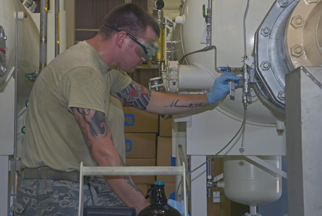 Senior Airman Robert Edmons, 374th Logistics Readiness Squadron fuels laboratory technician, takes a fuel sample from a tank at Yokota Air Base, Japan, Aug. 17, 2016. The sample is then taken to the laboratory to test for potential contamination before the fuel is provided to the aircraft. (U.S. Air Force photo by Senior Airman David Owsianka/Released)