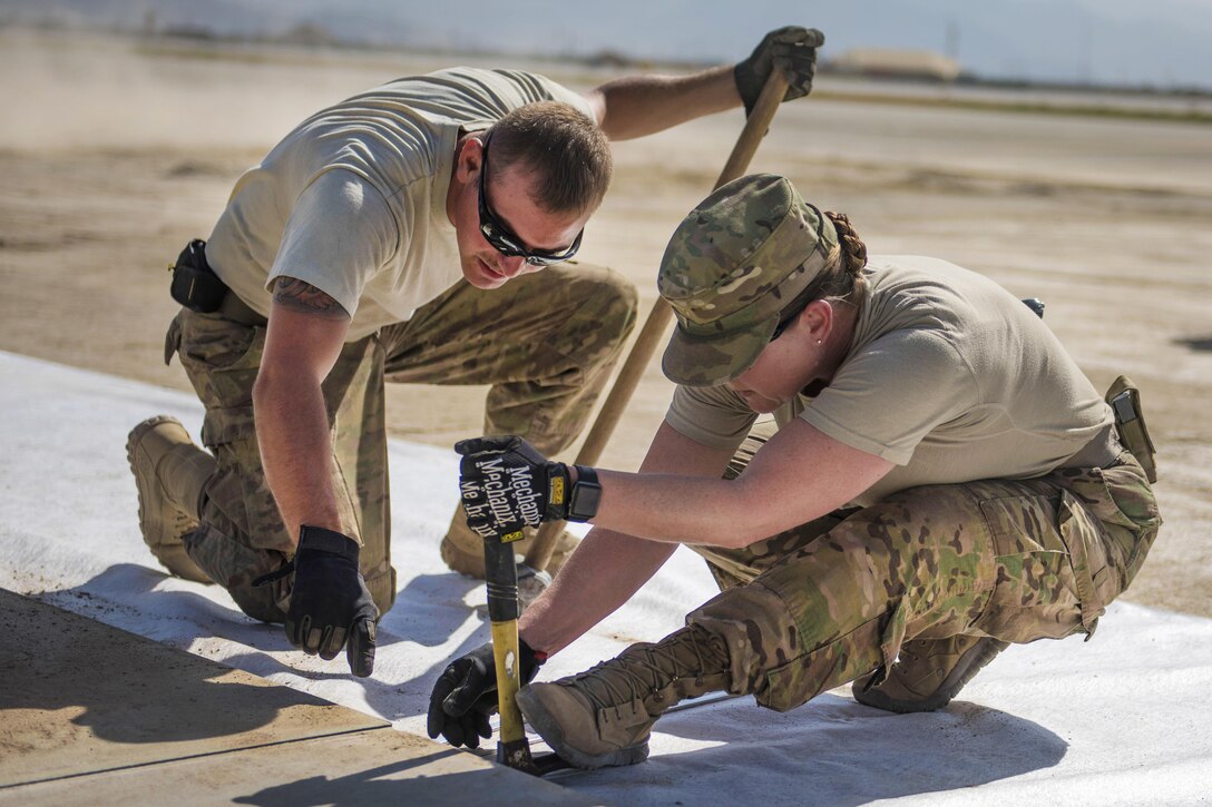 Air Force Master Sgt. Cassandra Doub, left, and Staff Sgt. Andrew Perna secure a piece of matting for a ramp expansion at Bagram Airfield in Afghanistan, Aug. 11, 2016. Doub is a first sergeant and Perna is a maintenance and equipment craftsman assigned to the 455th Expeditionary Civil Engineer Squadron. Air Force photo by Senior Airman Justyn M. Freeman