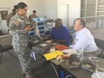 A soldier presents property to Wayne Willis (left), who was on hand at Foot Hood, Texas, from the DLA Disposition Services at Fort Sill, Oklahoma, while Peter Bechtel (right), from the Army’s office of Supply Policy and Programs, observes the process. 