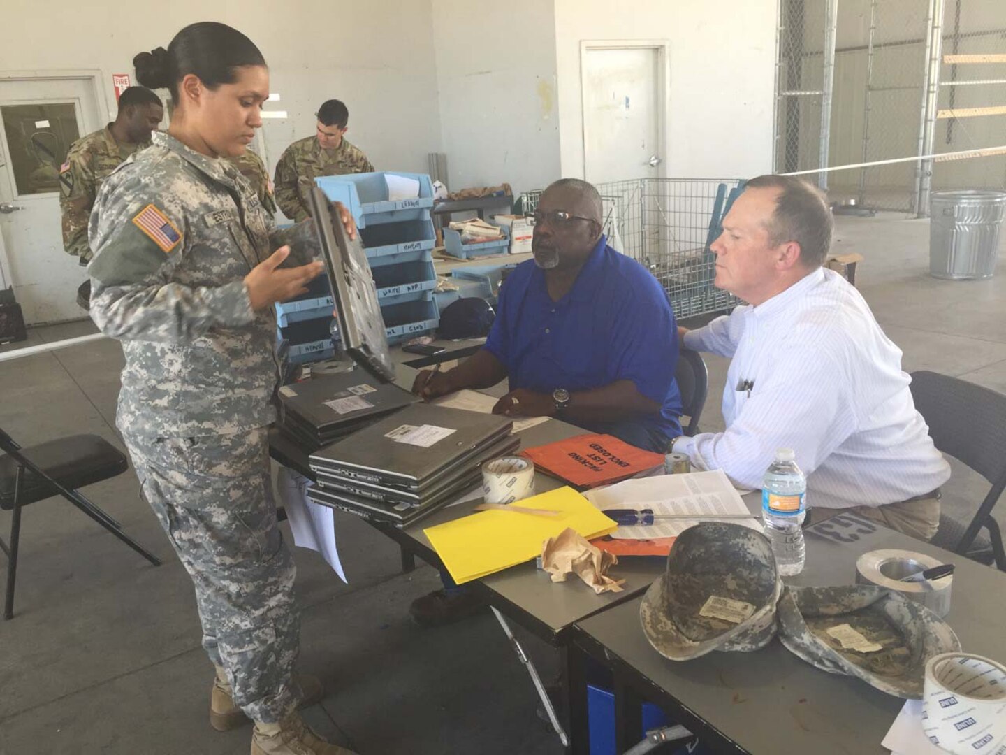 A soldier presents property to Wayne Willis (left), who was on hand at Foot Hood, Texas, from the DLA Disposition Services at Fort Sill, Oklahoma, while Peter Bechtel (right), from the Army’s office of Supply Policy and Programs, observes the process. 