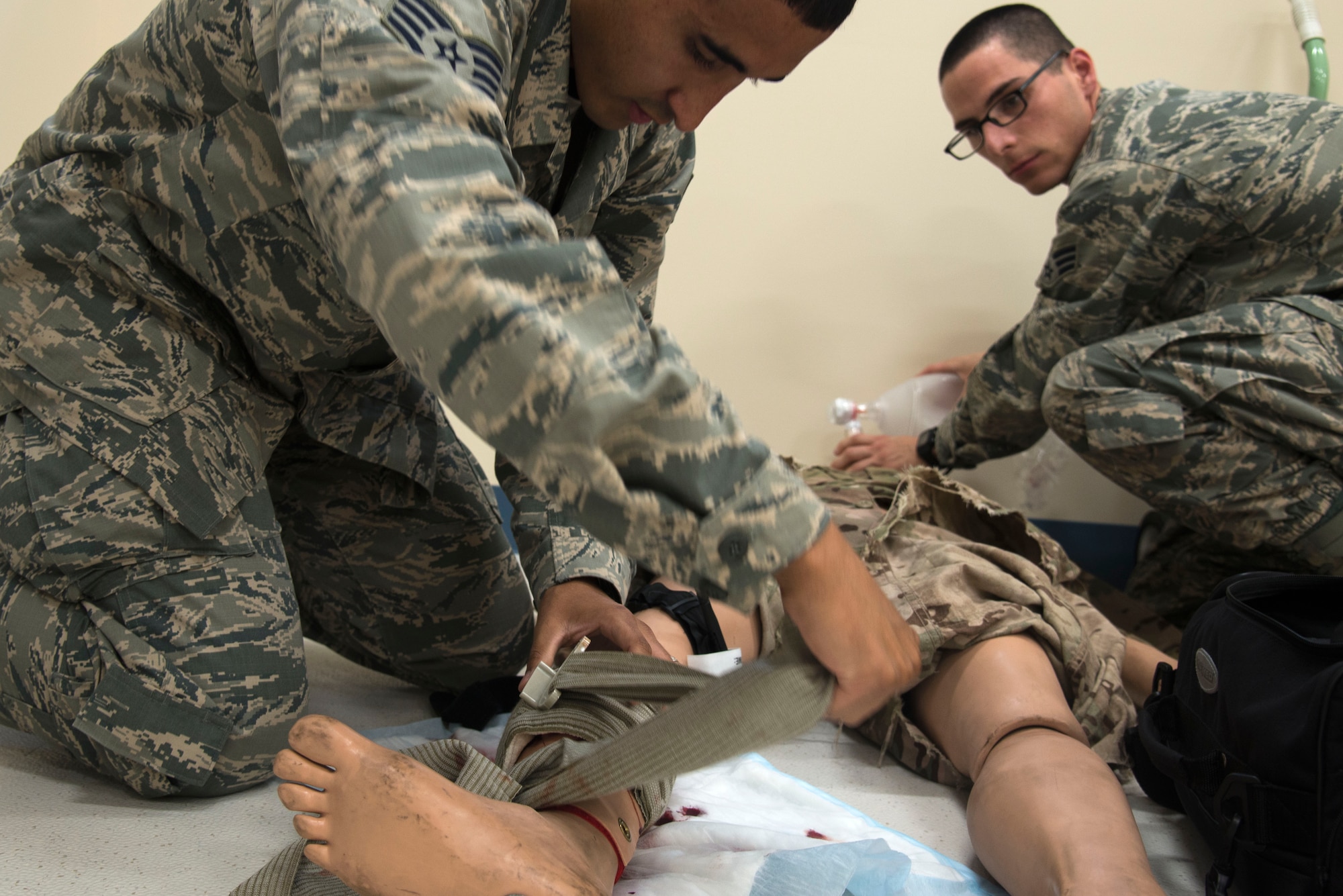 Senior Airman Chris Funn, 375th Medical Operations Squadron aerospace medical technician, performs assisted ventilation while Staff Sgt. Orlando Navarro, also an aerospace medical technician with the 375th MOS, applies a pressure bandage to a simulated blast patient while training for the Emergency Medical Technician Rodeo.(U.S.Air Force Photo by Airman Daniel Garcia)