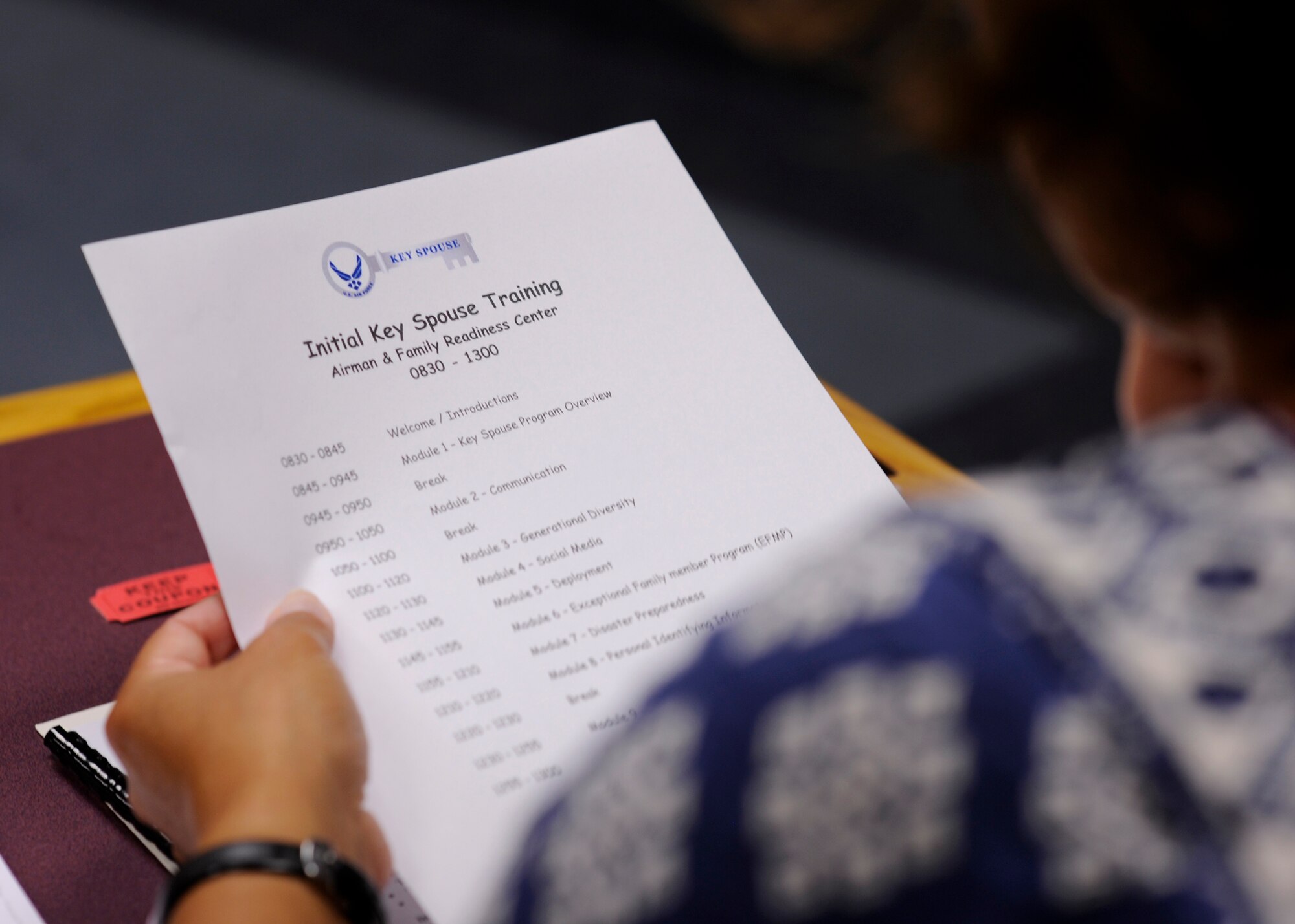 An individual looks over the key spouse training itinerary at the Airman & Family Readiness Center Aug. 16, 2016. New key spouses attended a six-hour training course, where they learned the importance of communication, disaster preparedness and resilience, within their new position and the role of the key spouse within the unit. (U.S. Air Force photo by Senior Airman Solomon Cook/Released)